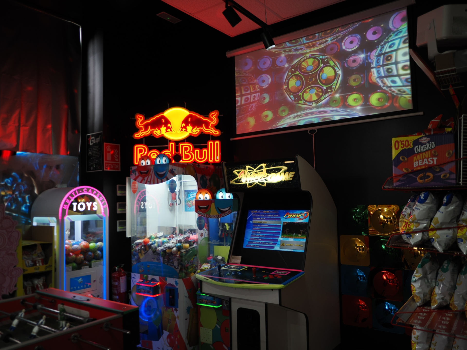 Zona de arcade con neón Red Bull, máquina de peluches y videojuegos