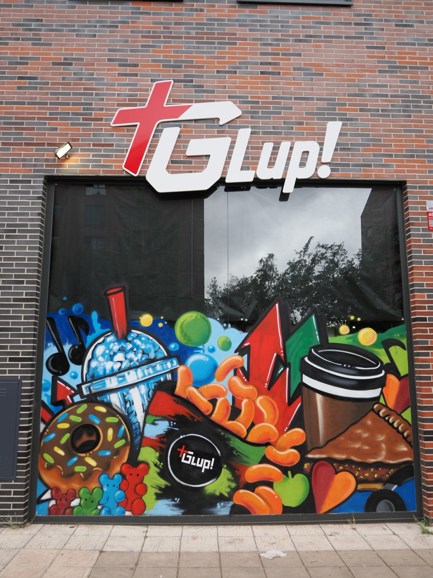Fachada de +Glup! en Zabalgana con mural de chuches, batidos y donuts